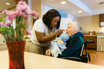 alzheimer patient holds doll while drinking water