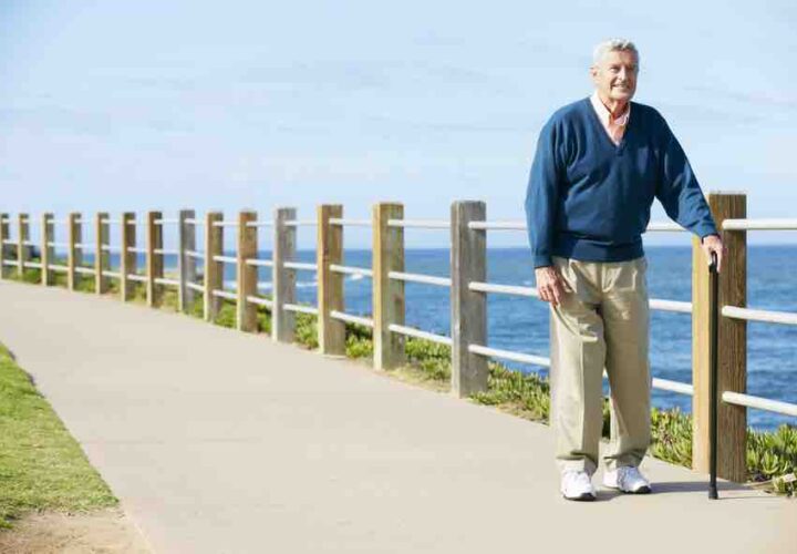 senior man walking with cane outdoors on walking path